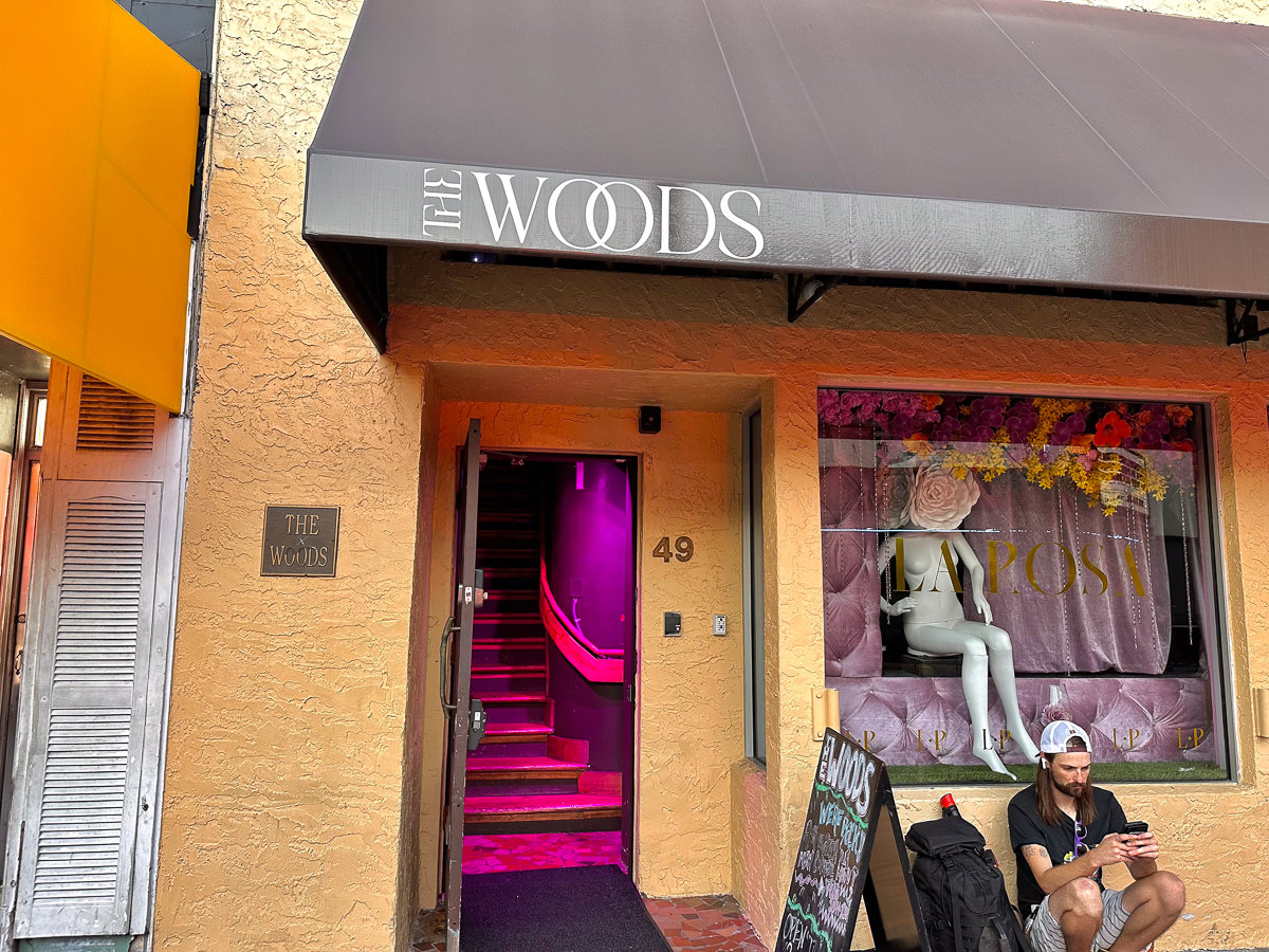 entrance to the woods bar with black awning and white lettering